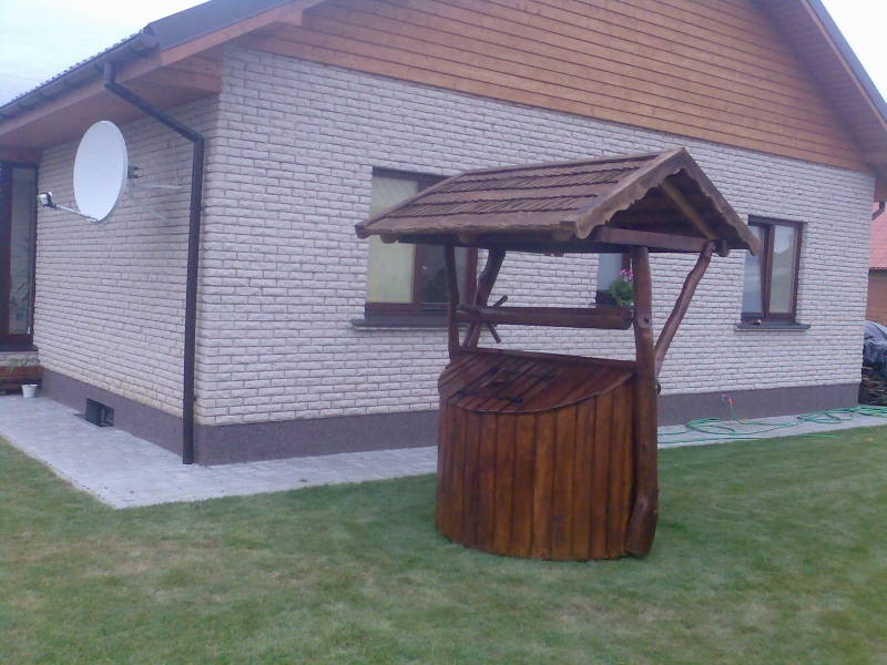 Decorative well with a round dark finish by a house No. 5